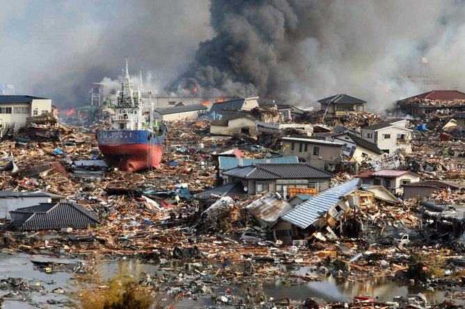 epa02628954 Amidst Tsunami flood waters burning houses and ships are piled in a mass of debris in Kisenuma city, Miyagi prefecture, Japan, 12 March 2011. A magnitude of 8.9 earthquake hit northern Japan on 11 March. EPA/STR JAPAN OUT